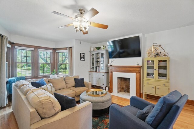 living room with a fireplace with flush hearth, wood finished floors, and ceiling fan