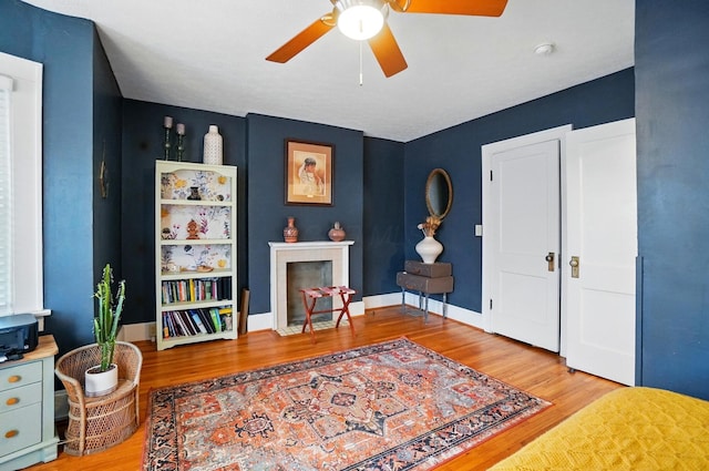 sitting room with ceiling fan, wood finished floors, and baseboards