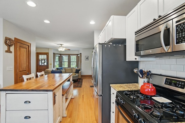 kitchen featuring appliances with stainless steel finishes, butcher block countertops, white cabinetry, open floor plan, and backsplash