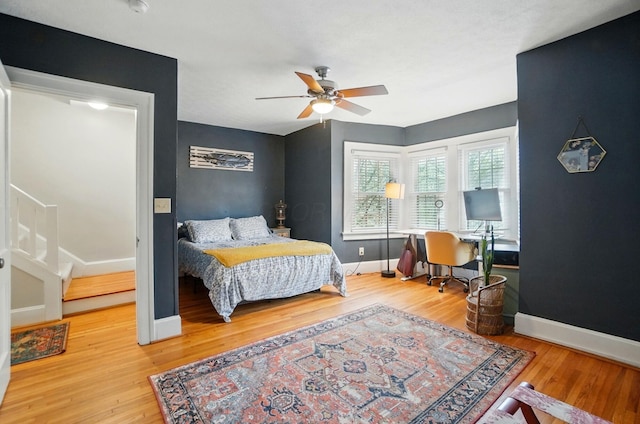 bedroom with wood finished floors, baseboards, a ceiling fan, and a desk