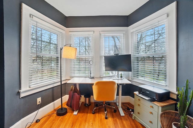 office space featuring healthy amount of natural light, wood finished floors, and baseboards
