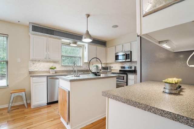 3998 Kul Cir S, Hilliard, OH 43026 - kitchen featuring a sink, stainless steel appliances, light wood-type flooring, a kitchen island with sink, and decorative backsplash