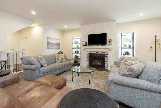 living area with recessed lighting, wood finished floors, a healthy amount of sunlight, and a glass covered fireplace
