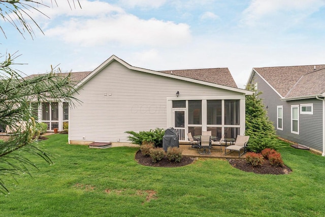 back of property featuring a lawn, a patio, a sunroom, and a shingled roof