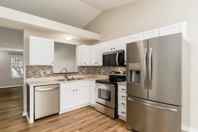 1409 Hackworth St, Columbus, OH 43207 - kitchen with stainless steel appliances, a sink, decorative backsplash, white cabinetry, and lofted ceiling