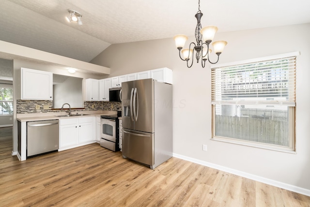 1409 Hackworth St, Columbus, OH 43207 - kitchen with appliances with stainless steel finishes, a sink, a chandelier, white cabinetry, and light wood-style flooring