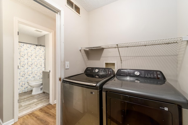 1409 Hackworth St, Columbus, OH 43207 - washroom featuring light wood-style floors, independent washer and dryer, and a textured ceiling