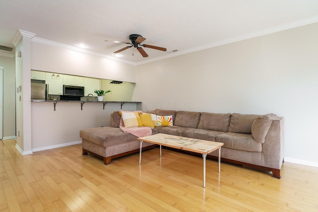 living area with ornamental molding, visible vents, ceiling fan, baseboards, and light wood-style floors