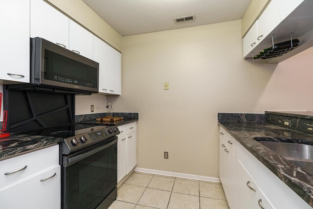 kitchen featuring stainless steel microwave, visible vents, white cabinets, black range with electric cooktop, and baseboards