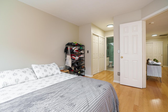 bedroom featuring ensuite bath, light wood-style flooring, baseboards, and a closet