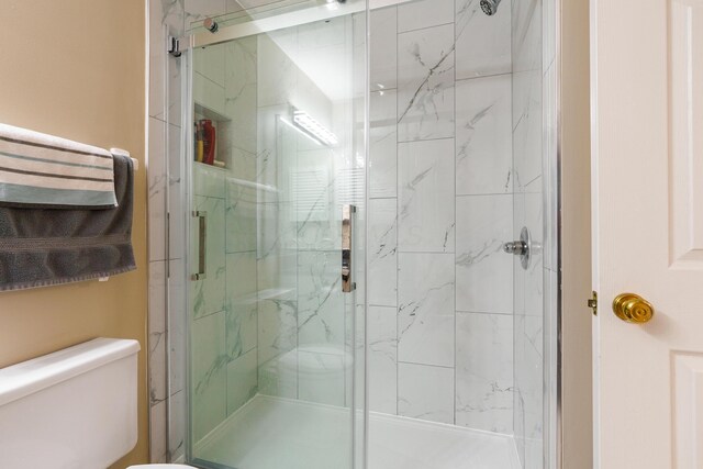 full bathroom featuring toilet and a marble finish shower