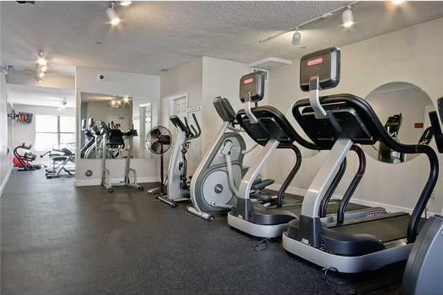 workout area featuring rail lighting, baseboards, and a textured ceiling