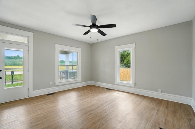 unfurnished room featuring plenty of natural light, visible vents, and wood finished floors