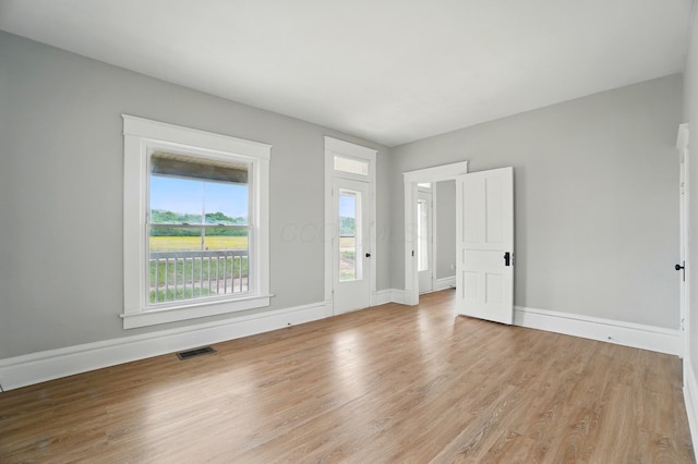 empty room with baseboards, light wood finished floors, and visible vents
