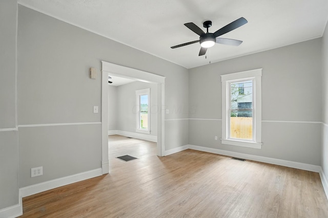empty room with plenty of natural light, visible vents, and wood finished floors