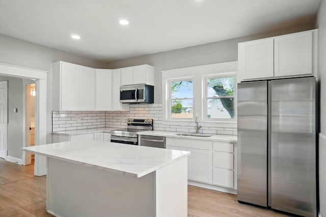 kitchen with a sink, stainless steel appliances, tasteful backsplash, and light stone countertops