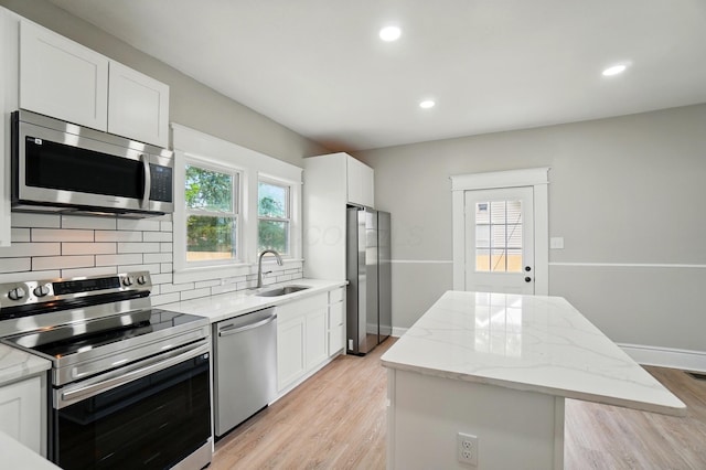 kitchen with a sink, stainless steel appliances, tasteful backsplash, a center island, and light wood-style floors