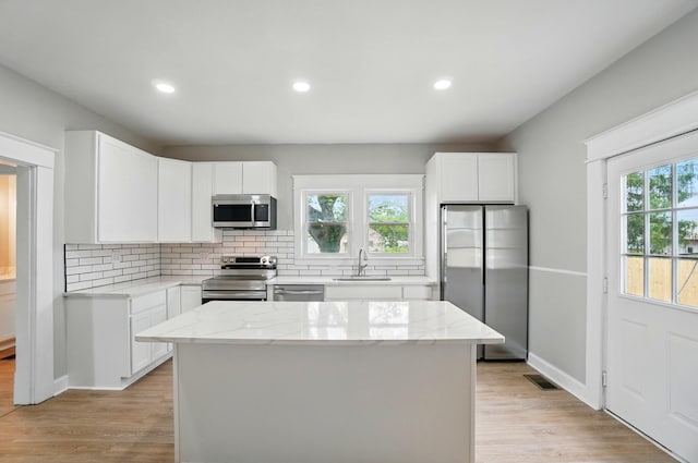 kitchen featuring a sink, stainless steel appliances, tasteful backsplash, visible vents, and light wood-style floors