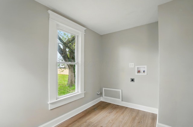 clothes washing area with laundry area, hookup for an electric dryer, light wood-style flooring, washer hookup, and baseboards