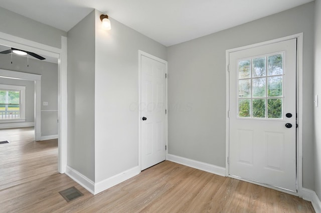 doorway to outside with light wood finished floors, visible vents, baseboards, and ceiling fan