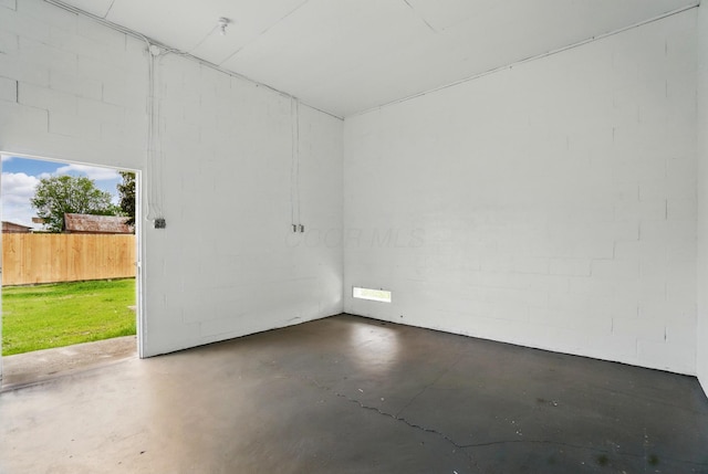 unfurnished room with concrete block wall and concrete flooring