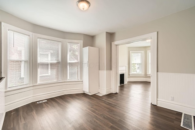 96 S Eureka Ave, Columbus, OH 43204 - unfurnished living room featuring healthy amount of natural light, a fireplace, dark wood-style flooring, and a wainscoted wall