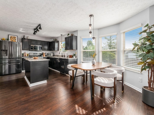 2284 Brisum Way, Hilliard, OH 43026 - kitchen featuring appliances with stainless steel finishes, a textured ceiling, a kitchen island, dark wood-style floors, and hanging light fixtures