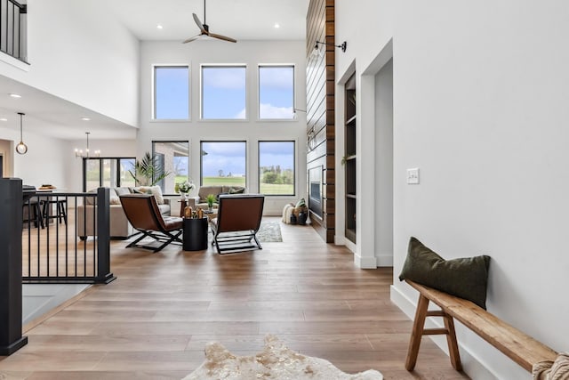 living area with light wood finished floors, a high ceiling, ceiling fan, and recessed lighting