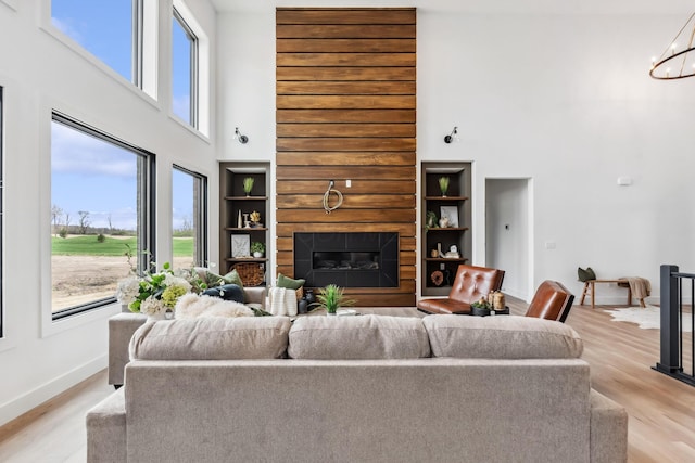 living area with a healthy amount of sunlight, light wood-type flooring, and a high ceiling