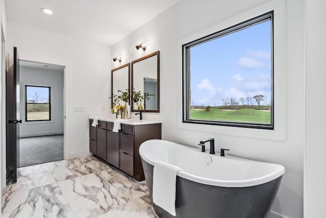 full bathroom with recessed lighting, baseboards, marble finish floor, vanity, and a freestanding bath