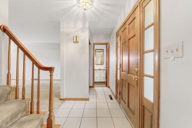 foyer with stairs, light tile patterned flooring, baseboards, and a textured ceiling