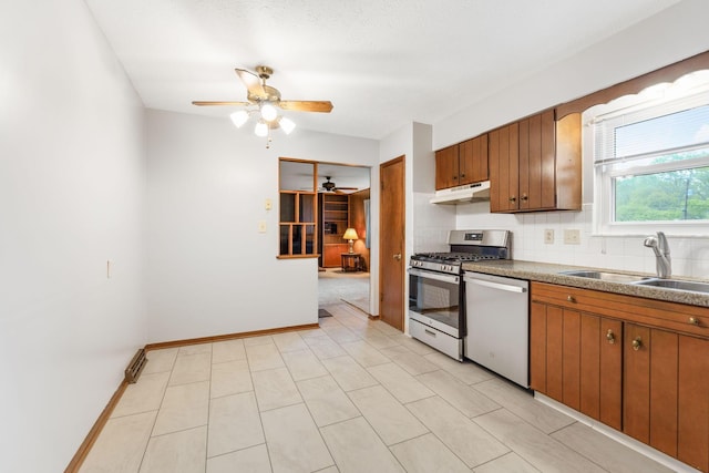 kitchen with stainless steel appliances, under cabinet range hood, a sink, a ceiling fan, and decorative backsplash