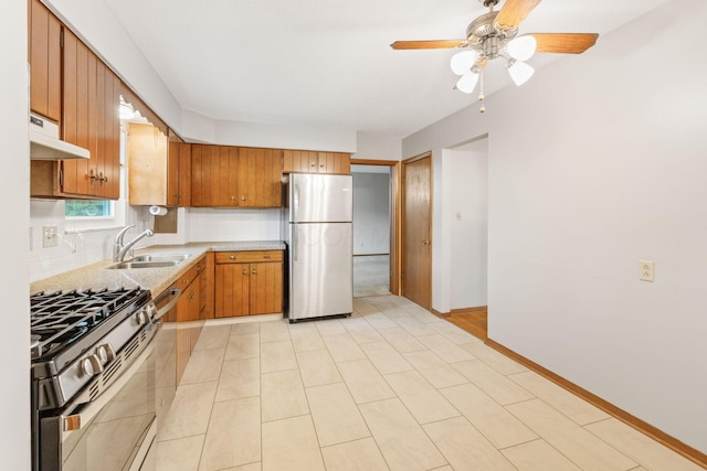 kitchen featuring appliances with stainless steel finishes, under cabinet range hood, light countertops, decorative backsplash, and brown cabinets