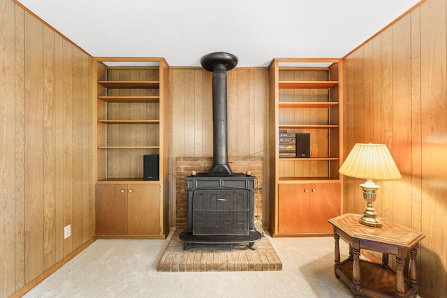 carpeted living room with a wood stove, wood walls, and built in features