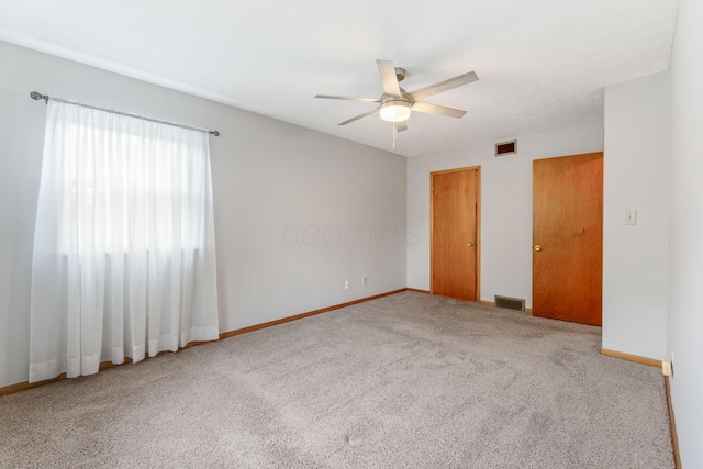 carpeted spare room with a ceiling fan and baseboards