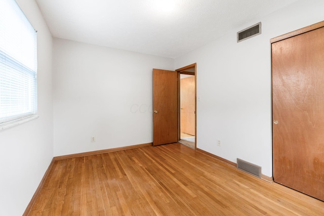 unfurnished bedroom featuring light wood-style flooring, baseboards, and a closet