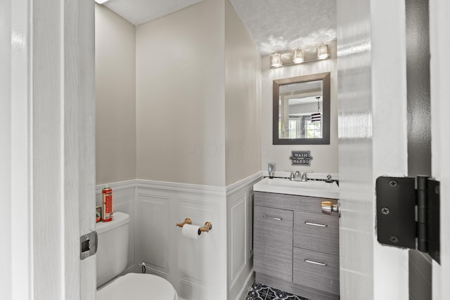 1301 Della Pl, Columbus, OH 43228 - bathroom featuring toilet, wainscoting, vanity, and a decorative wall