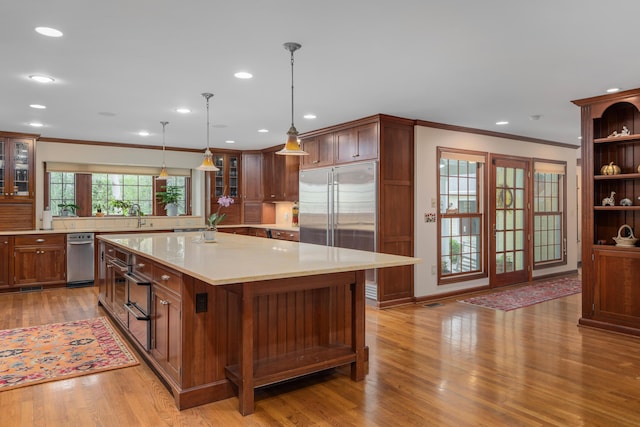 7870 Cook Rd, Plain City, OH 43064 - kitchen with light countertops, light wood-type flooring, ornamental molding, glass insert cabinets, and built in fridge