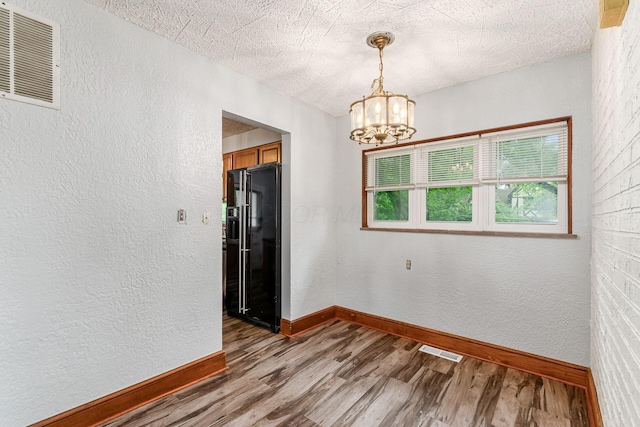 2584 E 5th Ave, Columbus, OH 43219 - spare room with a textured wall, wood finished floors, a chandelier, and a textured ceiling