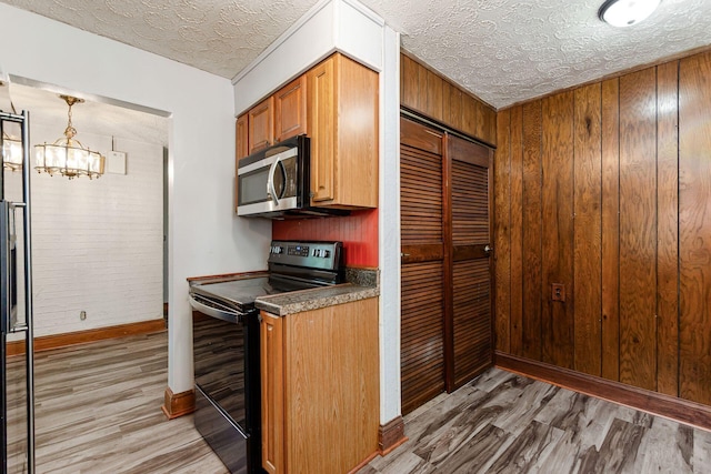 2584 E 5th Ave, Columbus, OH 43219 - kitchen featuring black electric range oven, stainless steel microwave, light wood-style flooring, a textured ceiling, and a chandelier