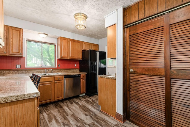 2584 E 5th Ave, Columbus, OH 43219 - kitchen with stainless steel dishwasher, black fridge with ice dispenser, wood finished floors, a textured ceiling, and light countertops