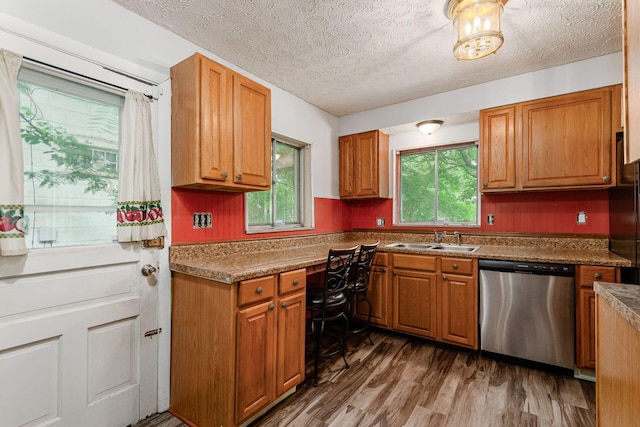 2584 E 5th Ave, Columbus, OH 43219 - kitchen with stainless steel dishwasher, wood finished floors, a textured ceiling, and brown cabinetry