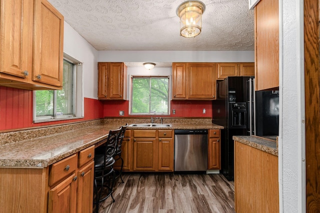 2584 E 5th Ave, Columbus, OH 43219 - kitchen featuring stainless steel dishwasher, healthy amount of natural light, black fridge, wood finished floors, and a textured ceiling