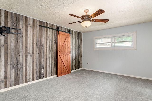 2584 E 5th Ave, Columbus, OH 43219 - empty room with a textured ceiling, a barn door, a ceiling fan, carpet, and wood walls