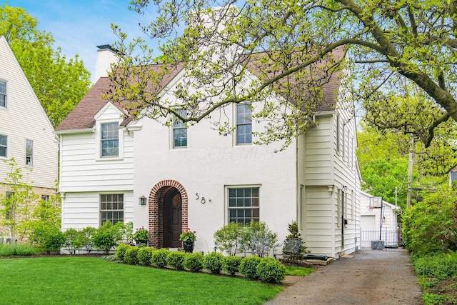 traditional-style home featuring a chimney, a front lawn, and a garage