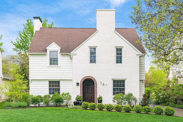 tudor home with a chimney and a front yard
