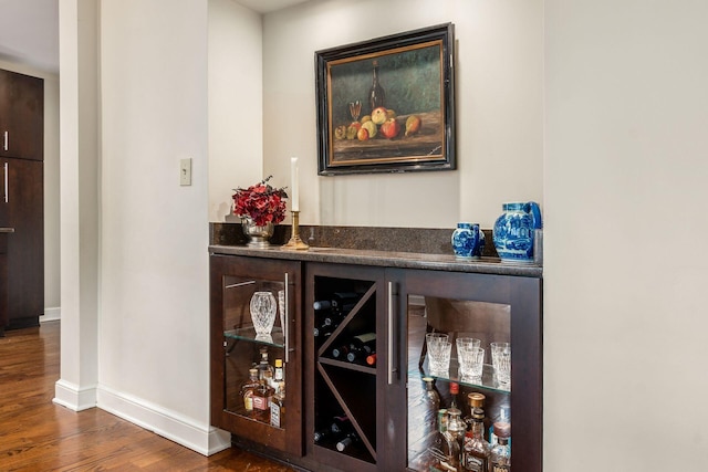 indoor dry bar with wood finished floors and baseboards