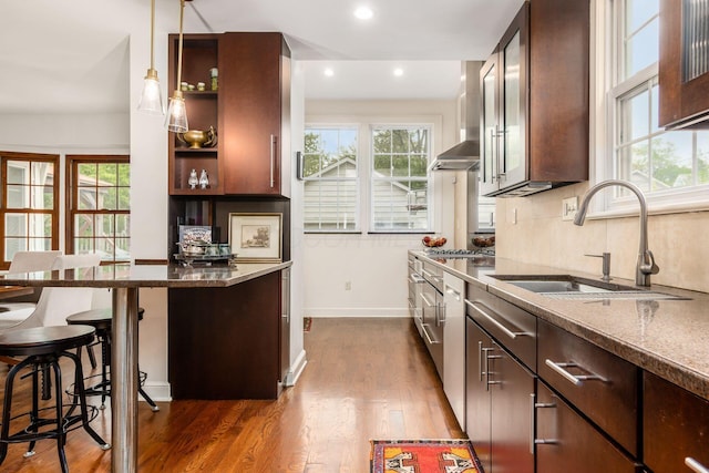 kitchen with a sink, dark brown cabinetry, dark stone counters, dark wood-style flooring, and a kitchen breakfast bar