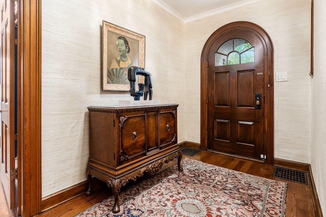 foyer entrance featuring crown molding, wood-type flooring, baseboards, and arched walkways