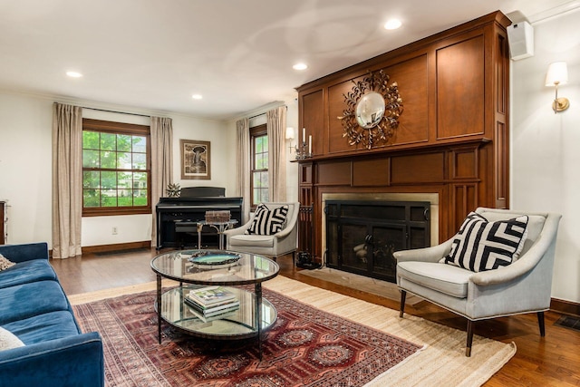 living area featuring wood finished floors, a fireplace, baseboards, recessed lighting, and crown molding